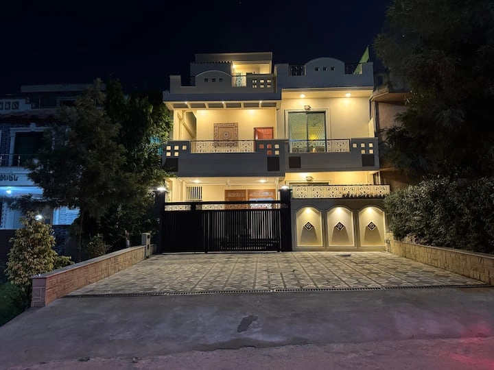 Night view of a modern guest house in Islamabad with bright exterior lighting, spacious driveway, and elegant architectural design for 2026 stays.